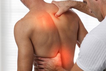 Man experiencing upper back muscle pain during physical therapy session